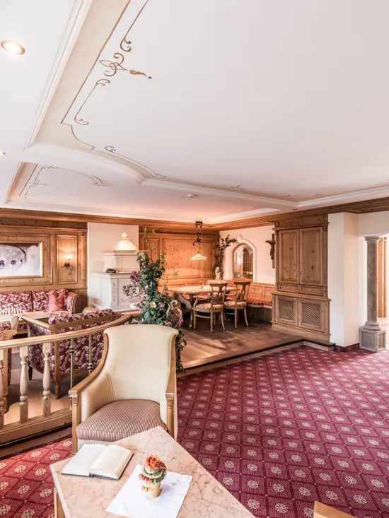 Gemütliche Hotellounge mit alpinen Holzmöbeln und rotem Teppich mit Muster